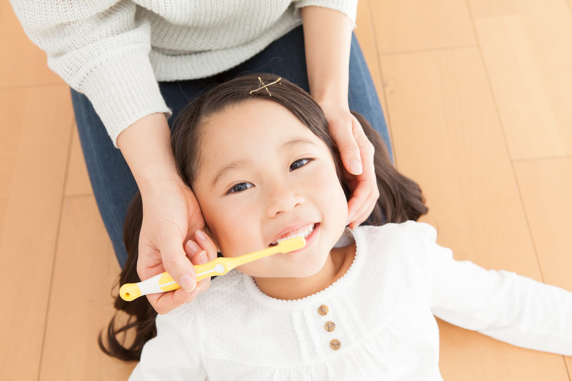 歯石がつかないように仕上げ磨きをしてもらっている子ども